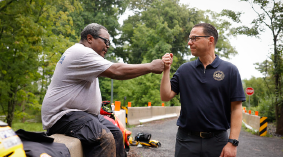 Governor Shapiro fist bumps with a man at the site of a flood.